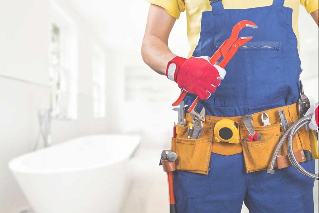 plumber with tool belt standing in bathroom